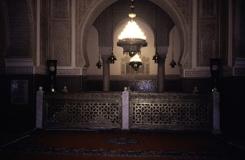 ASC Leiden - van Achterberg Collection - 07 - 035 - Two burning lanterns above a railing between two grandfather clocks in a mosque. Medersa Bou Inania - Meknes, Morocco - Early 1990s — Fez